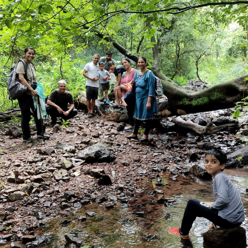 Kids and adults posing along side a fallen tree and stream of water at CEC BNHS